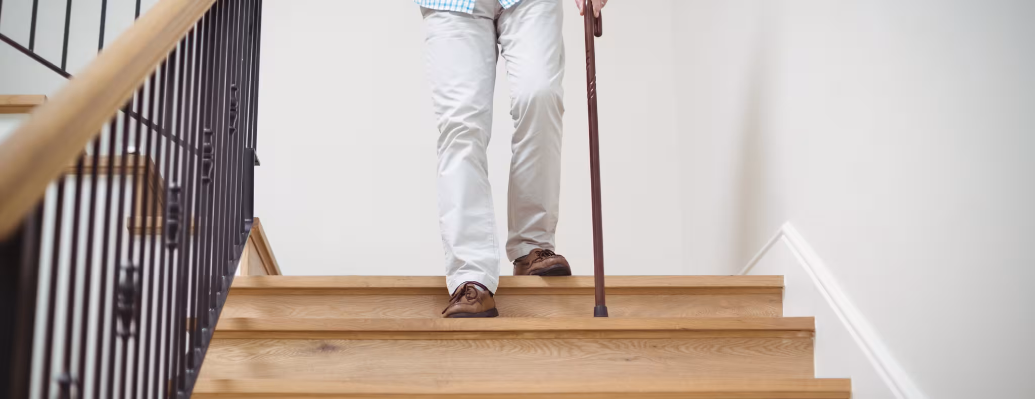 Senior man climbing downstairs with walking stick