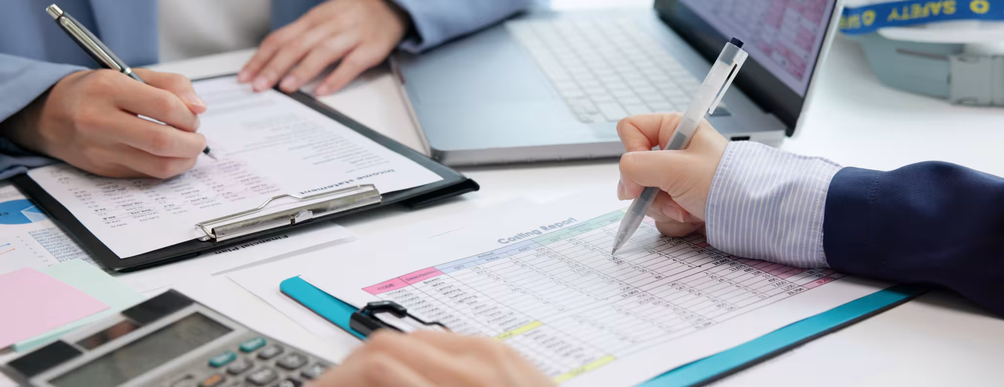 People at a table reviewing paper and electronic financial statements.
