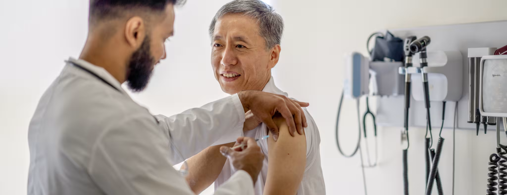 A male doctor administering a medical injection into a senior patient's arm.