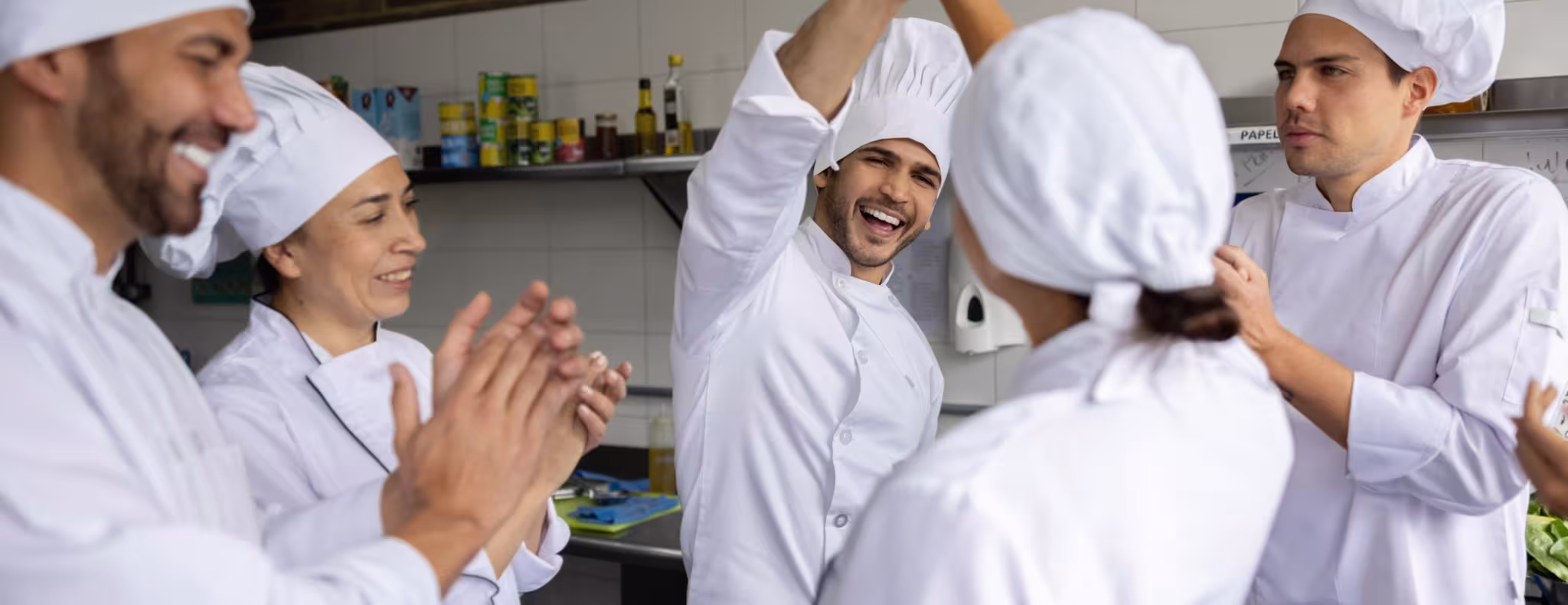 Happy team of chefs high-fiving in the kitchen of a restaurant and smiling