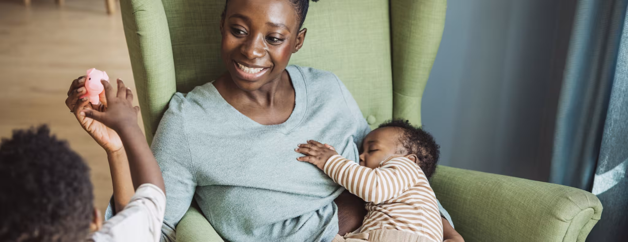 Young mother breastfeeding baby while playing with toddler
