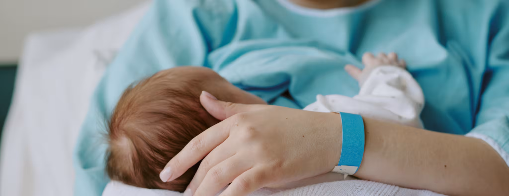 Mother Breastfeeding Newborn Baby in Hospital Room