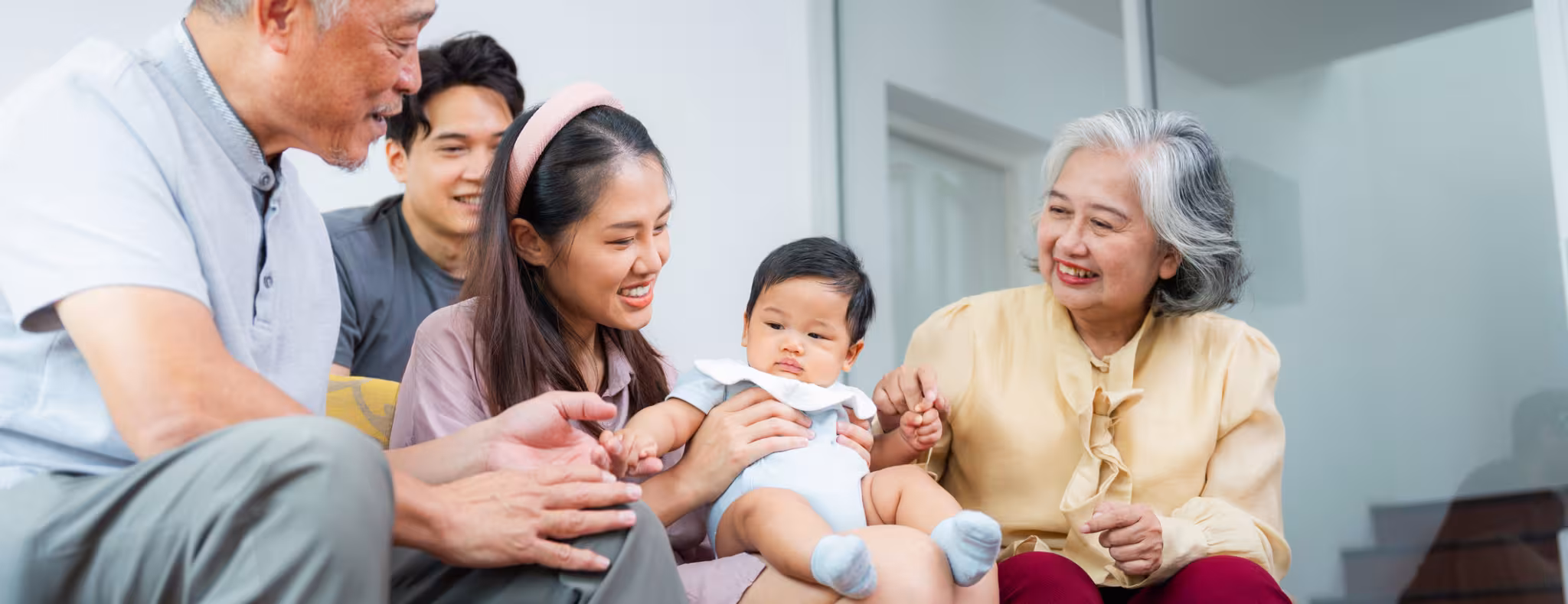 Cheerful Asian Grandparents, Parents, and Child Relaxing Together on Couch,