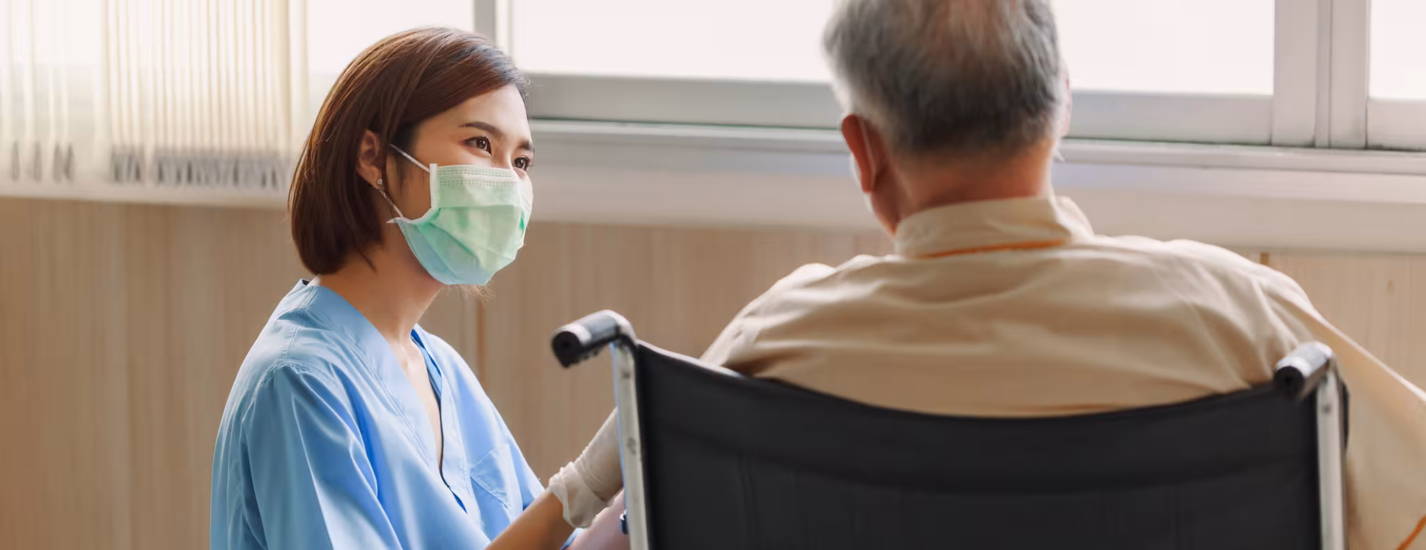 Young Asian woman nurse explaining information to elderly man patient in wheelchair 
