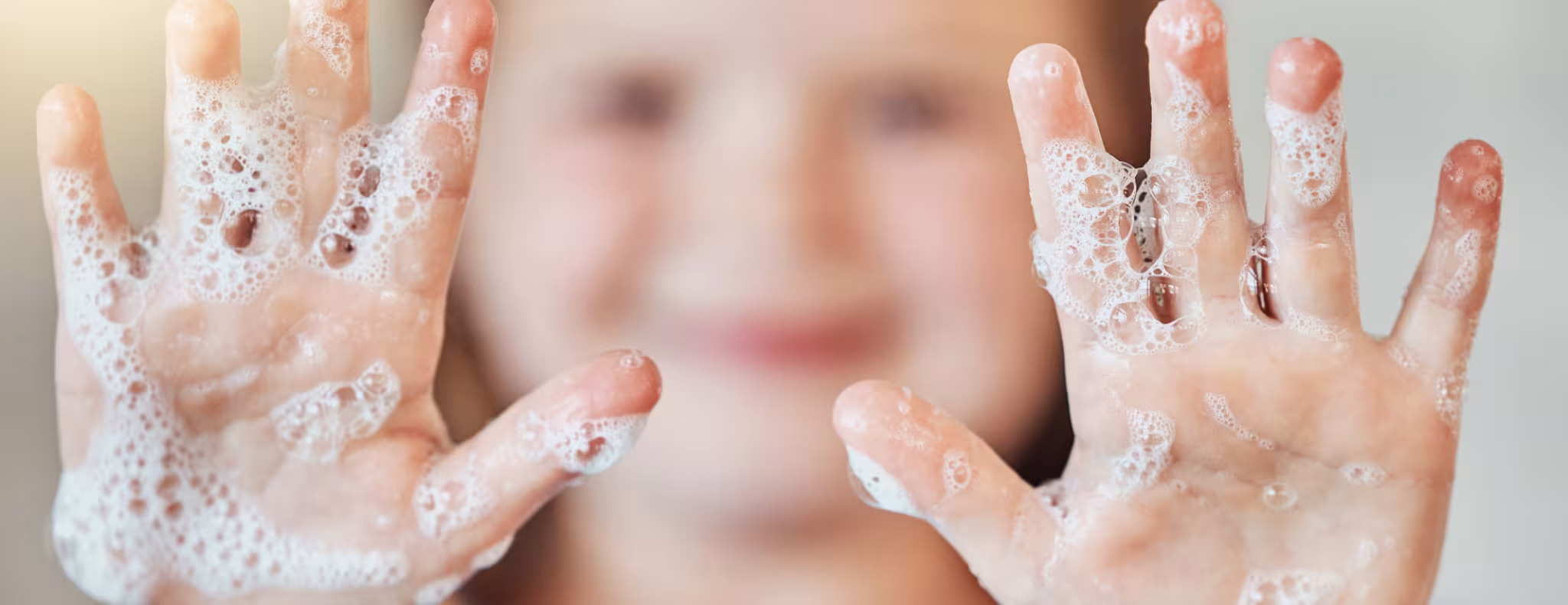Girl holding her soapy hands up to the camera