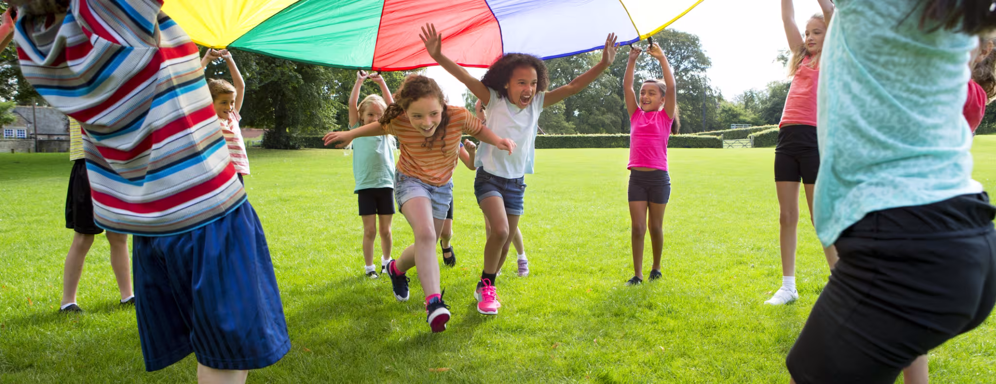 Children playing a game with a colourful Parachute