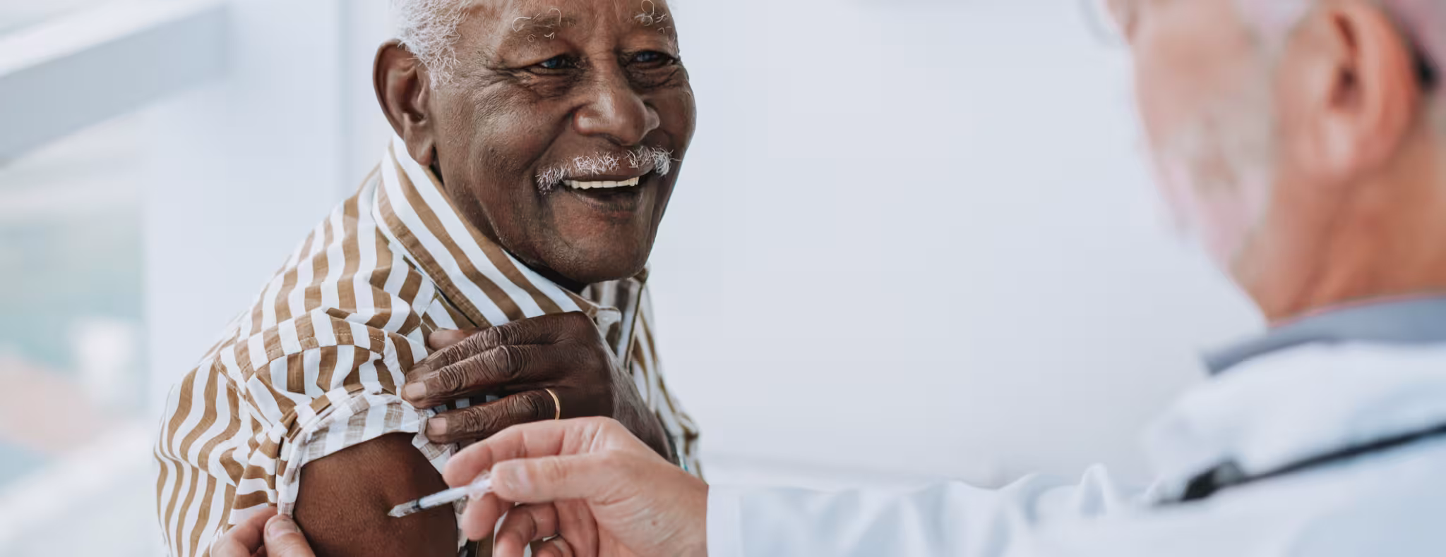 A doctor giving a vaccine to a smiling senior patient.