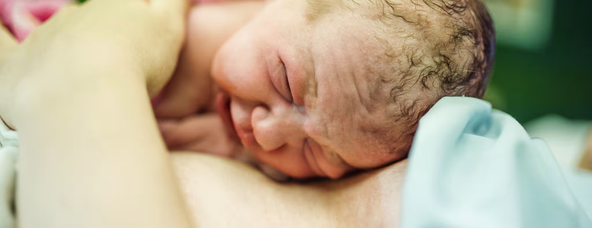 Beautiful baby girl few minutes after the birth lying on her mother, skin to skin contact