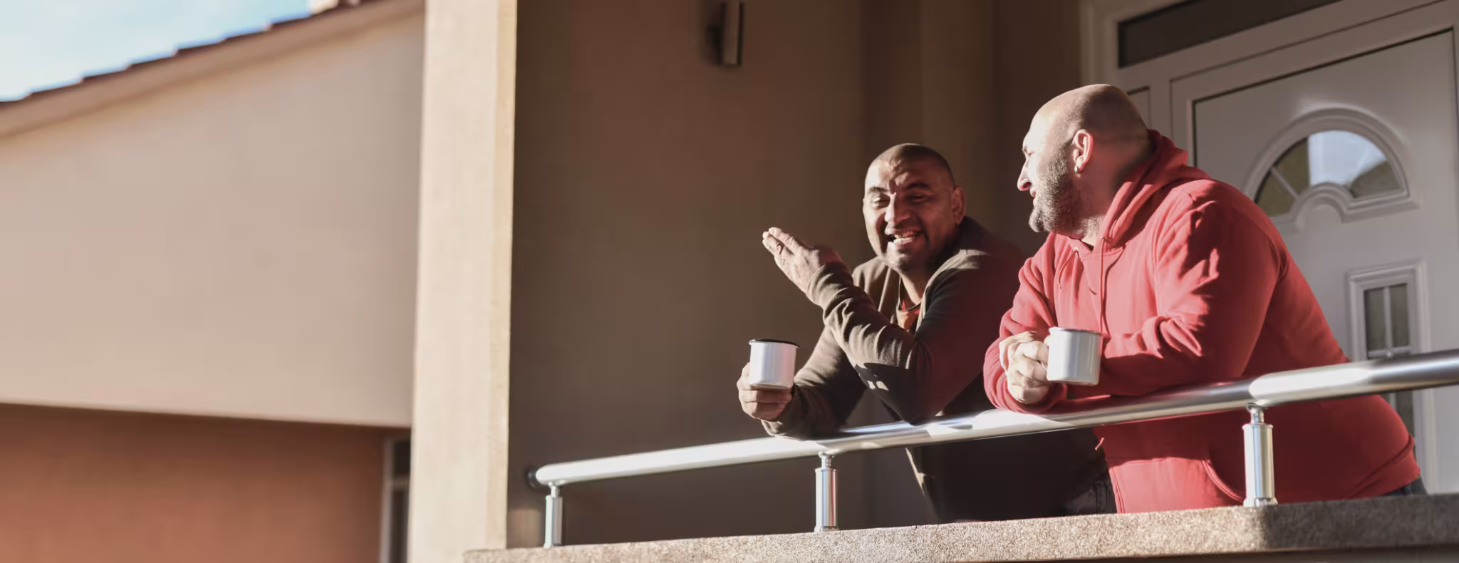Two males enjoying coffee on their balcony