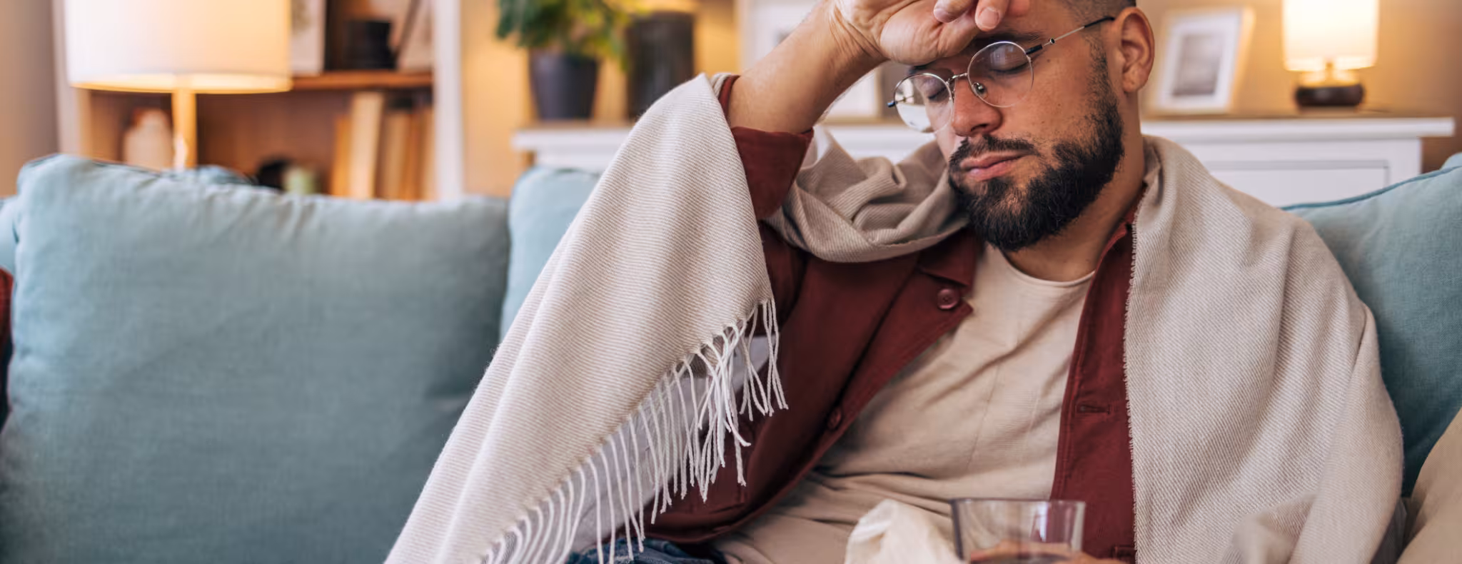 A mid-adult sick man sitting on the sofa in the living room