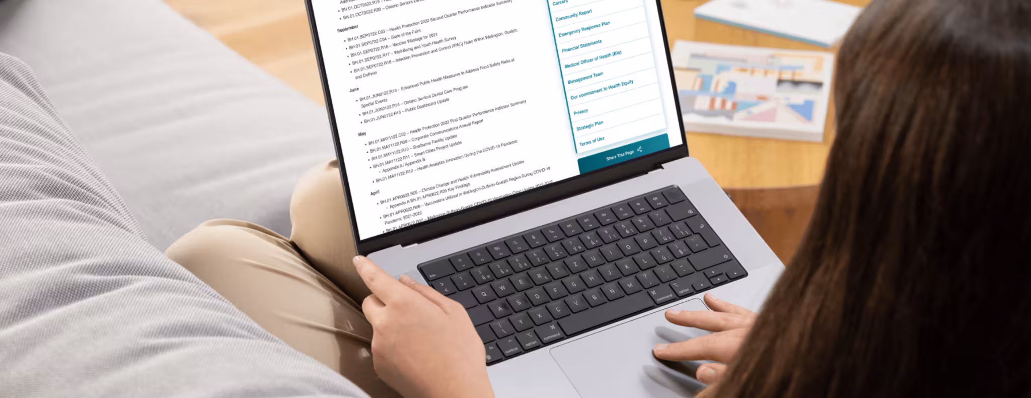 Woman sitting on couch looking at this web page on her laptop