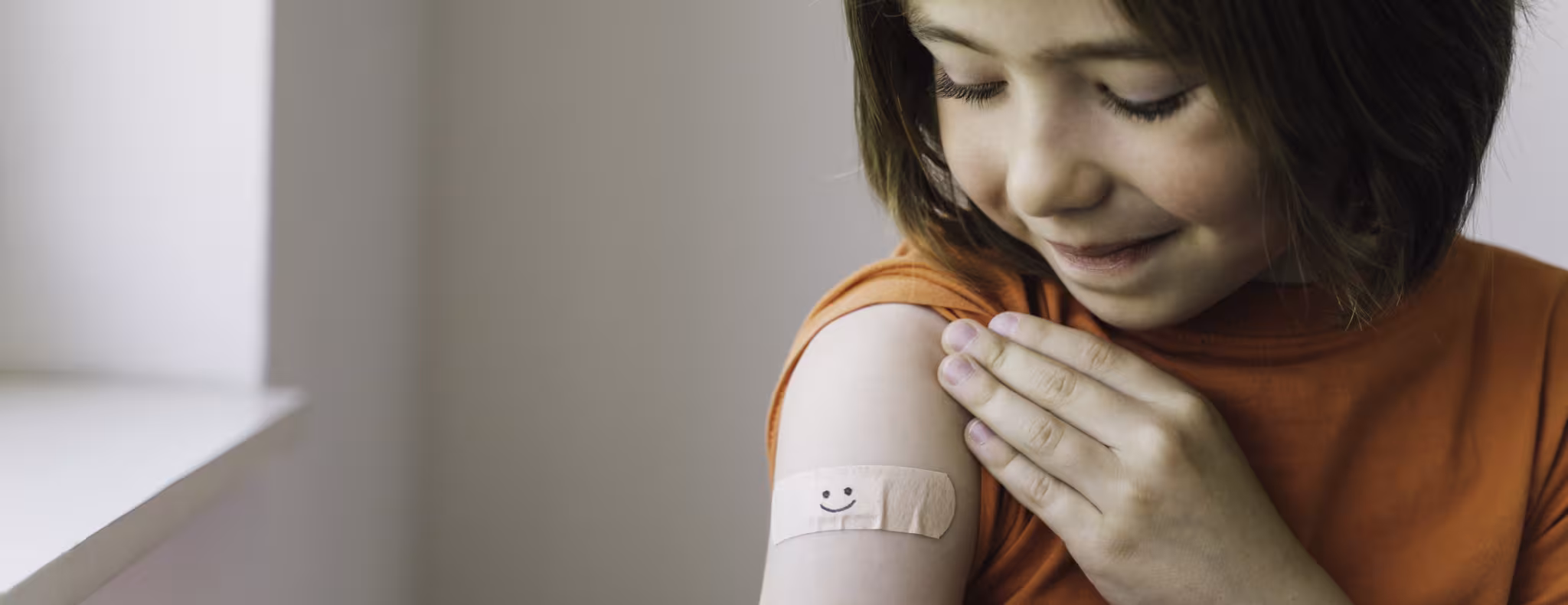 Child looking at her arm with a bandaid just got vaccinated