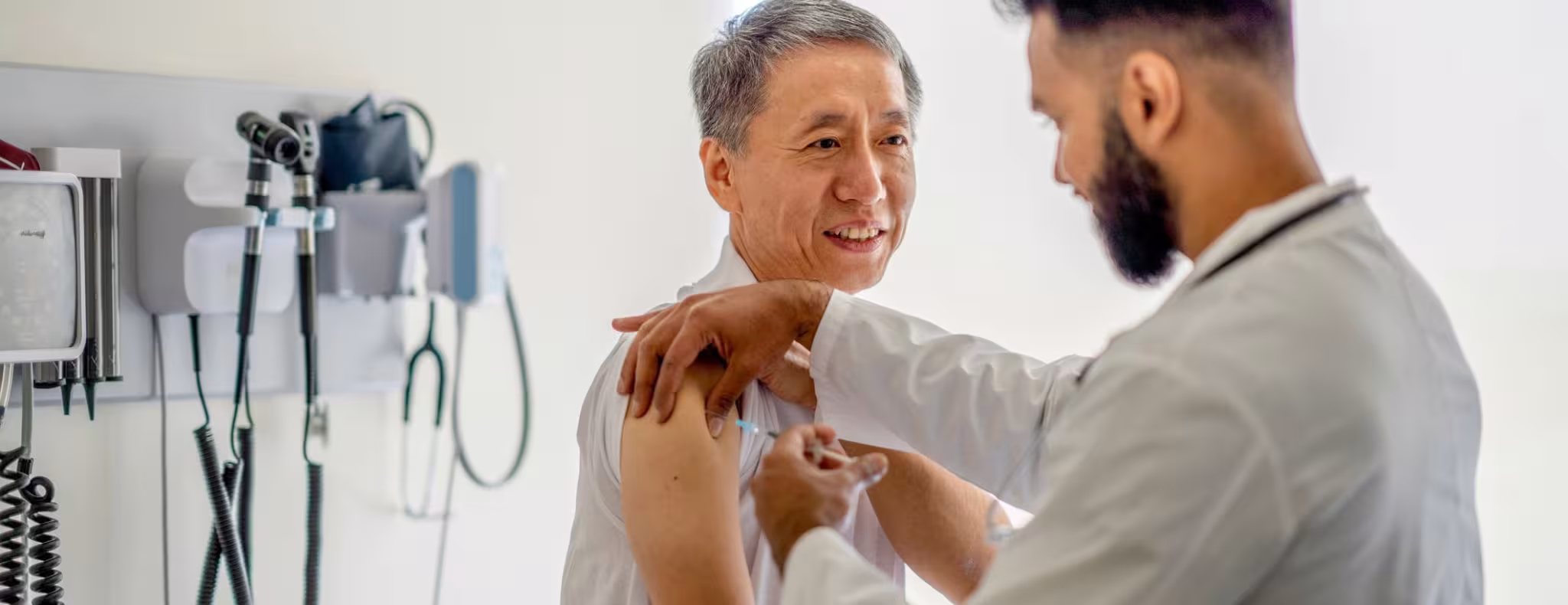 A male doctor administering a medical injection into a senior patient's arm.