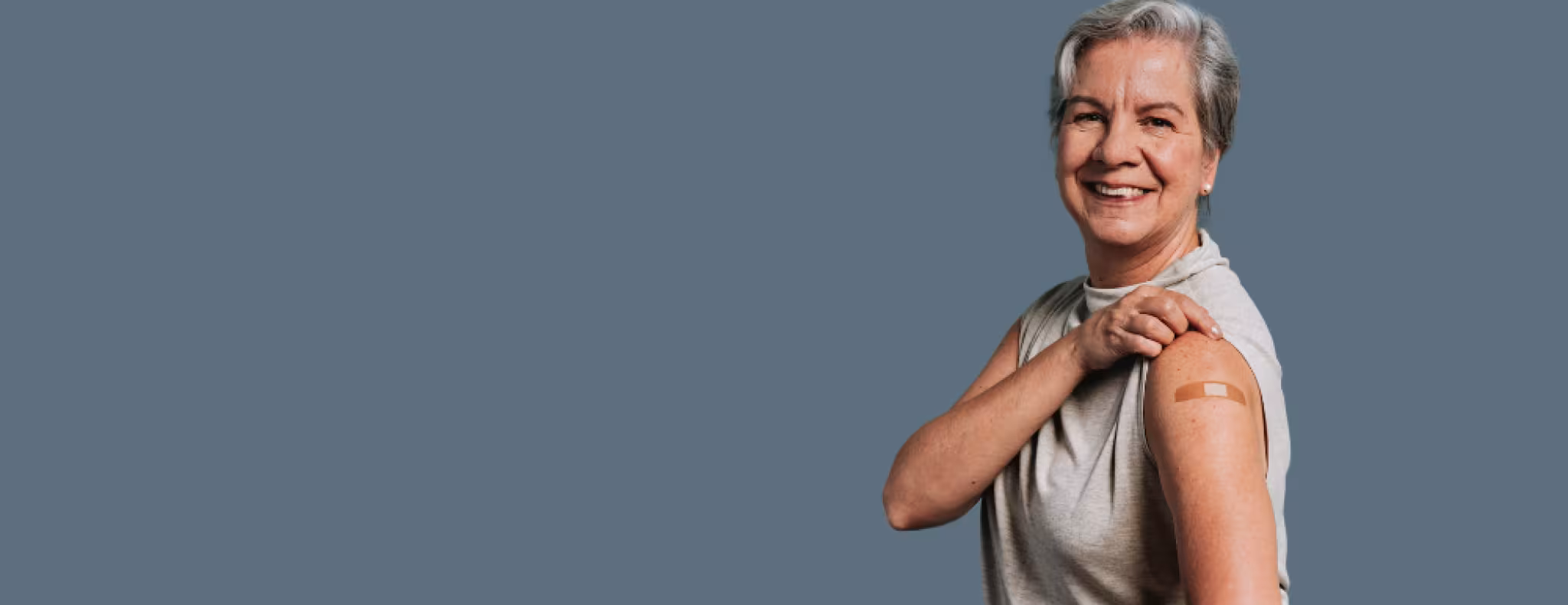 Senior woman showing bandaid on arm after vaccination